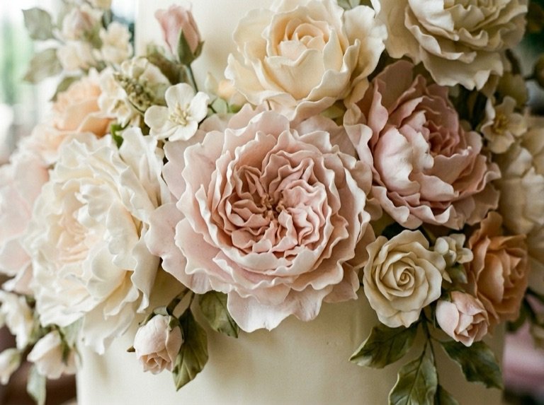 Close detail of the blush and cream sugar peonies and roses massed on the tier
