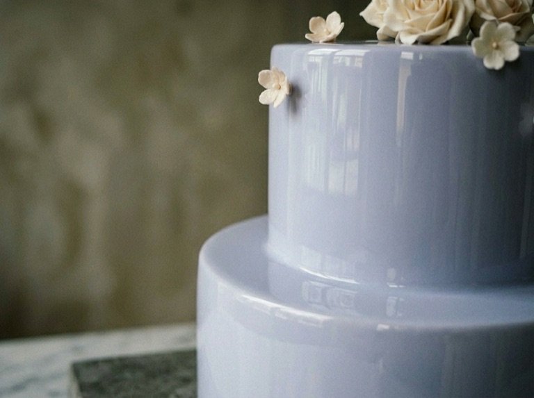 Close detail of the mirror-clean periwinkle glaçage with a single hand-set sugar blossom