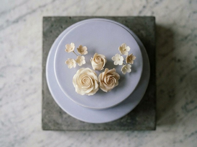 Overhead view of cream sugar roses and blossoms set on the periwinkle top tier