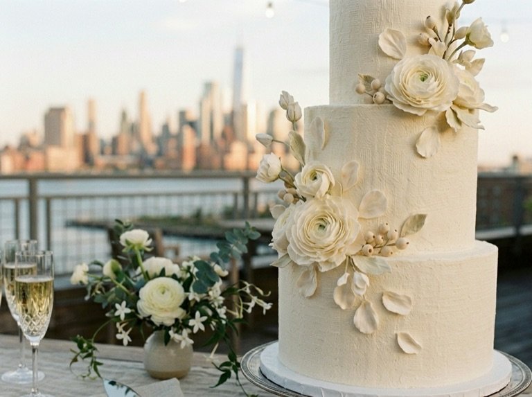 Three-tier ivory wedding cake finished with hand-piped sugar ranunculus